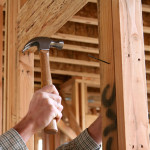 A handsome construction man using a hammer to nail together wood